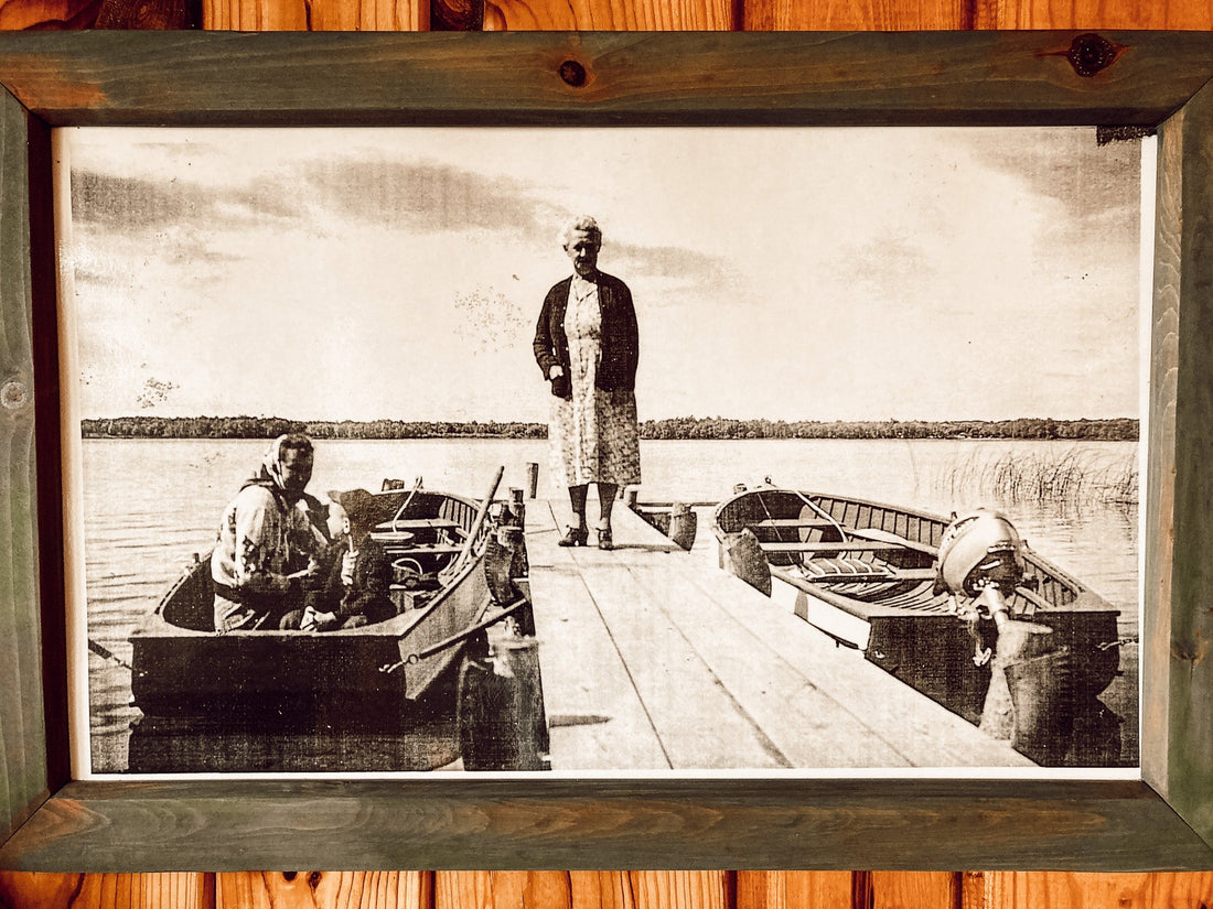 Image from 50's, woman standing on dock with another woman in a boat.
