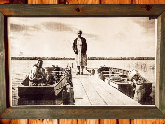 Image from 50's, woman standing on dock with another woman in a boat.